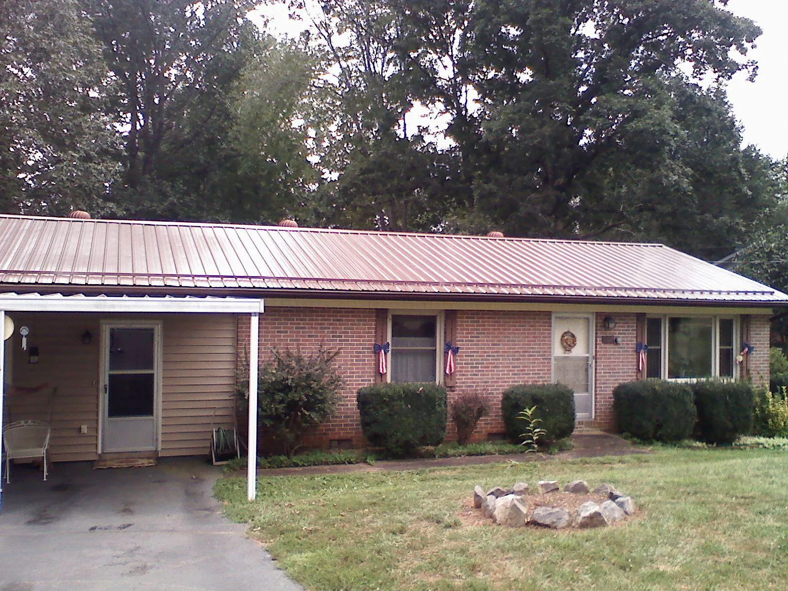 Bronze metal roof and carport on a brick ranch home — Roof Repair work by our crew in Raymond